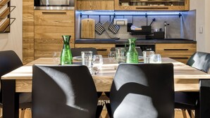 Eine moderne Küche mit Holzschränken, Edelstahlgeräten und einem Essbereich mit Tisch für vier Personen.
