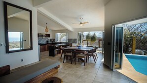 A spacious kitchen with a dining area, a large window, and a view of the outdoors. - Casa Cumbre PXM (Santa María Colotepec)