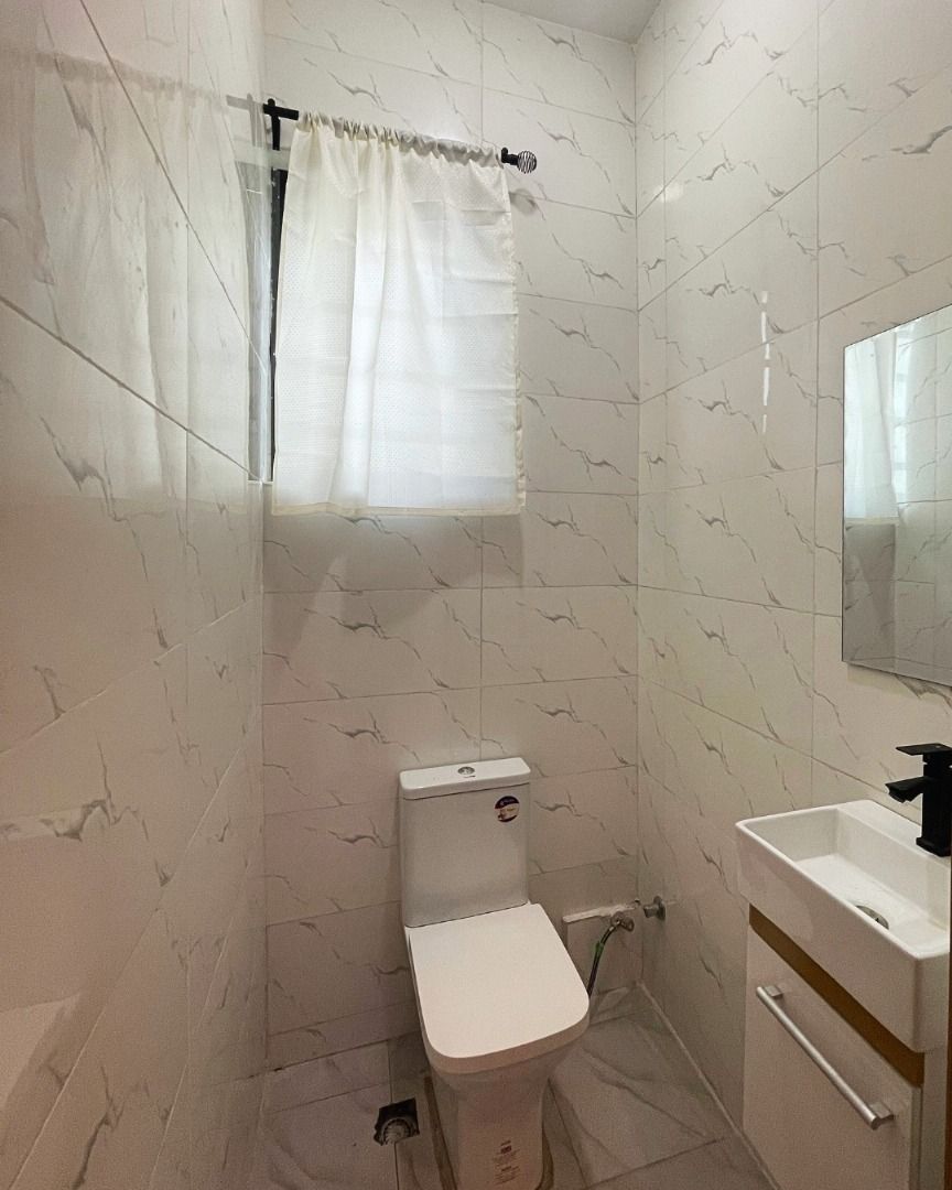 A small bathroom with a toilet, a sink, and a shower curtain.