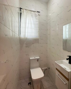 Een kleine badkamer met toilet, wastafel en douchegordijn.