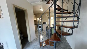 A spiral staircase with metal railings and wooden steps leading to an upper floor. - Residencial Encantos Linha Bonita (Gramado)