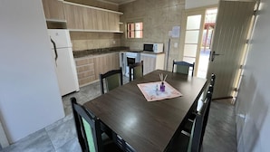 A modern kitchen with a dining table, chairs, and a microwave. - Residencial Encantos Linha Bonita (Gramado)