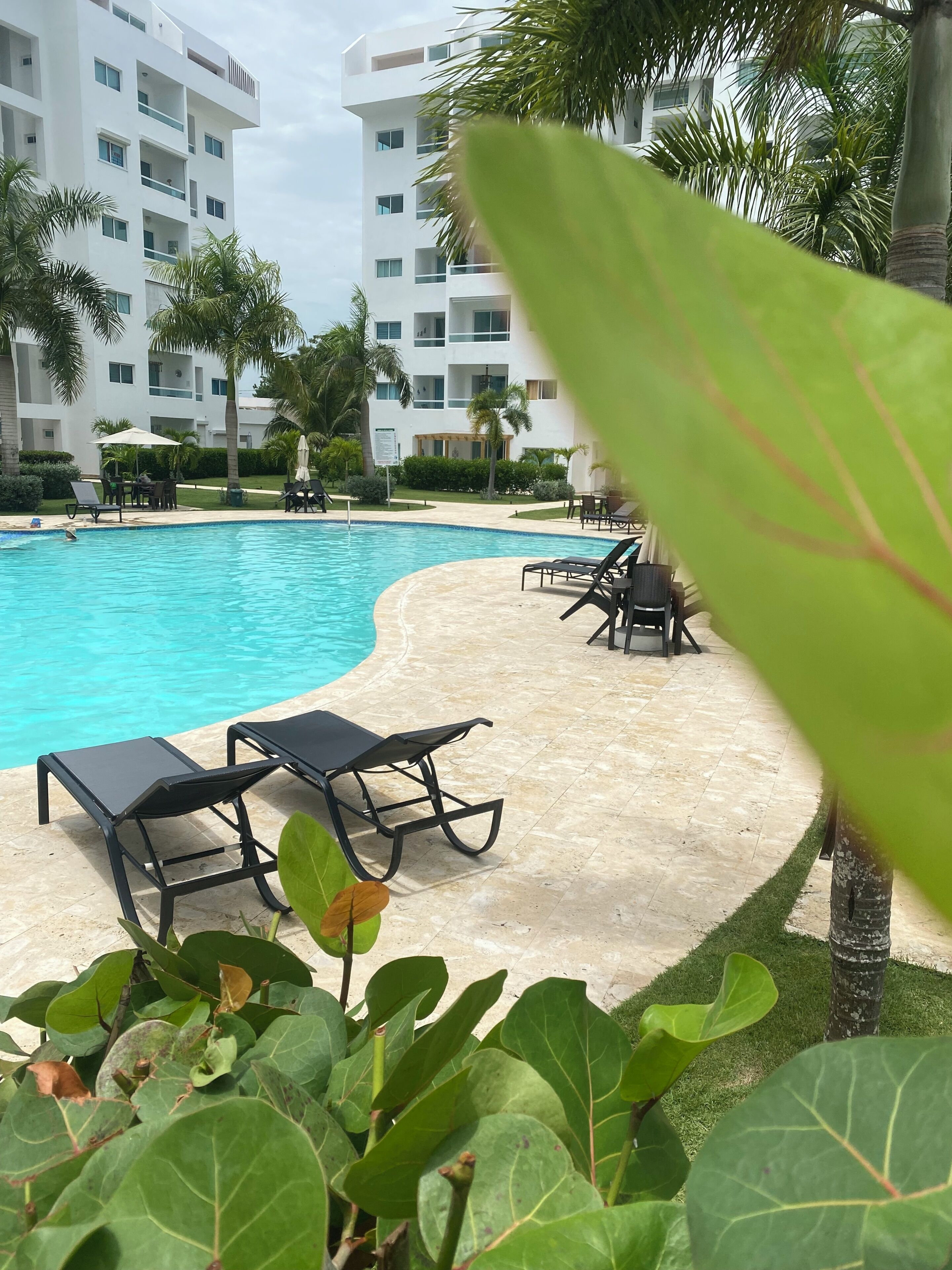 Une piscine avec des chaises longues et un bâtiment en arrière-plan.