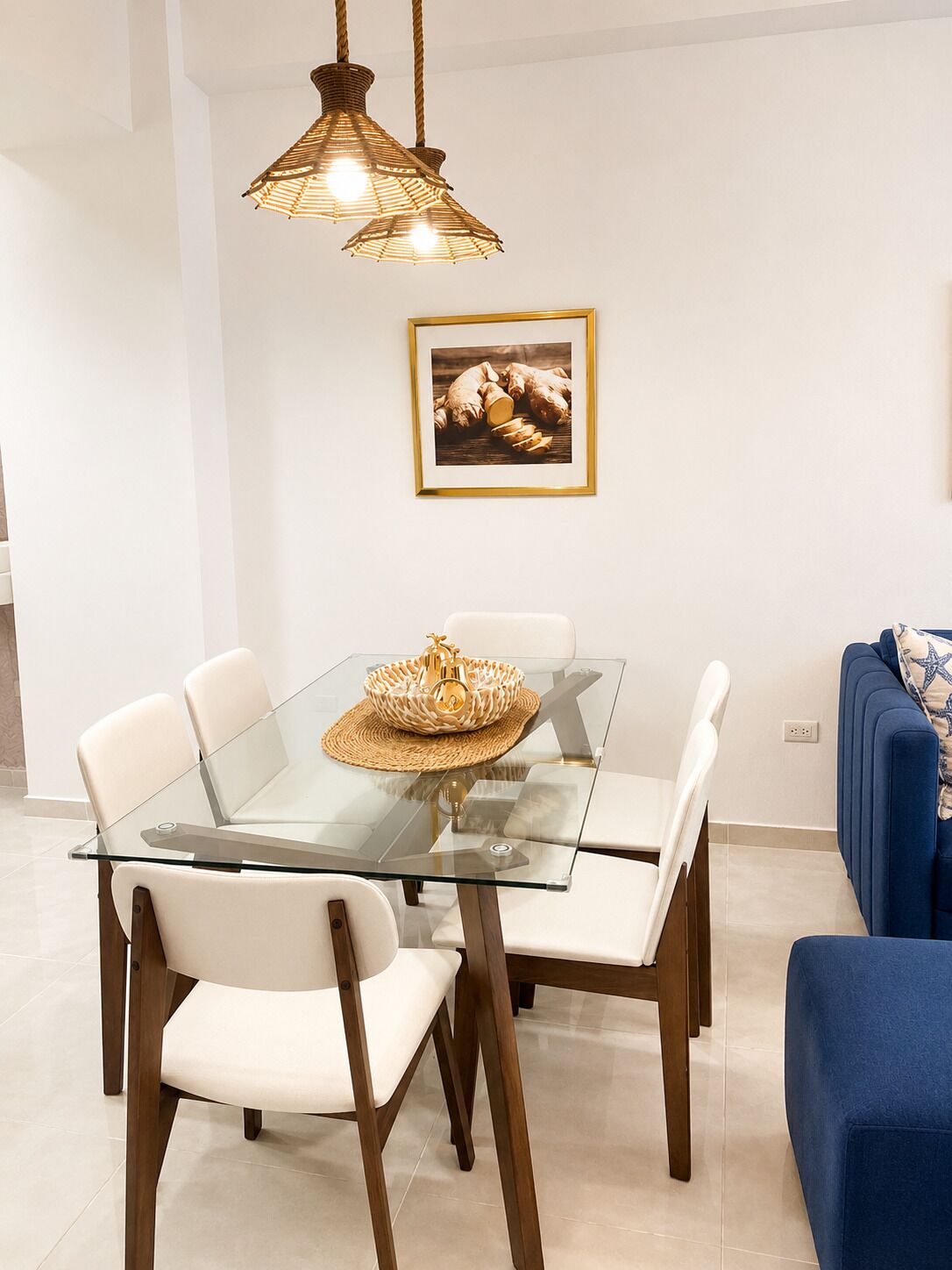 A dining area with a glass table, white chairs, and a woven centerpiece.