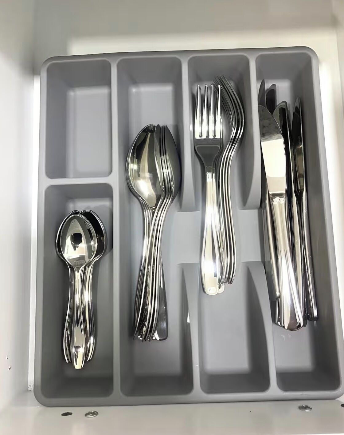 A compartmentalized tray with utensils including a spoon, fork, and knife.