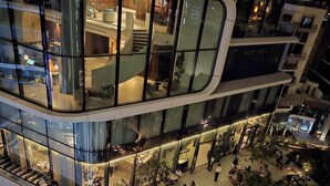 Un atrio de varios niveles con zonas de estar abiertas, plantas de interior y una disposición circular central para sentarse.