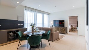 Una sala de estar moderna con un sofá, televisor, mesa de comedor, sillas y una zona de cocina.