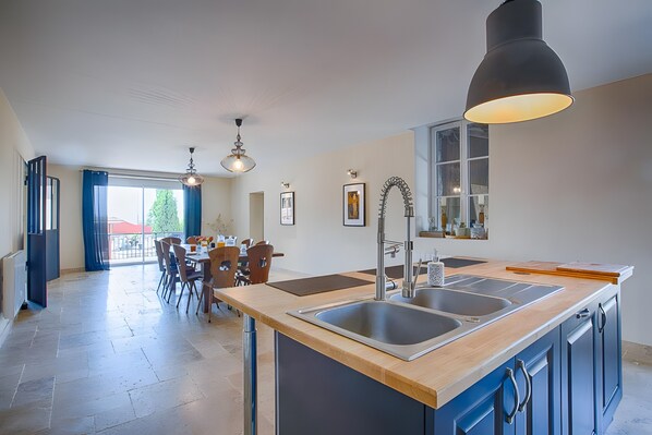 Una cocina moderna con una isla grande, un lavamanos doble e iluminación colgante.