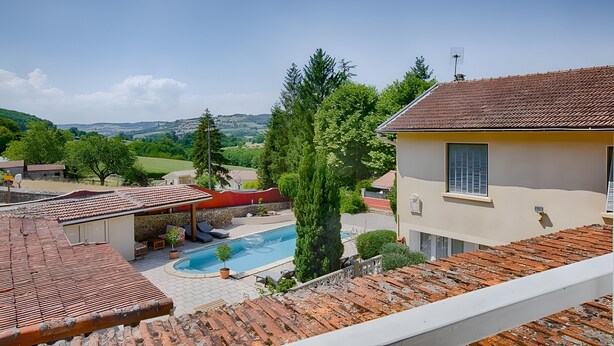 Ein Wohnhaus mit Pool, überdachter Terrasse und Blick ins Grüne.