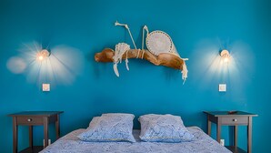 Ein Bett mit blauer Musterdecke, zwei Nachttische und Wandleuchten.