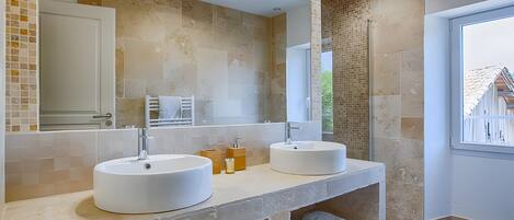 Un baño moderno con dos lavamanos, un espejo grande y vistas al exterior.