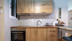 Una cucina compatta con mobili in legno, forno integrato e lavello.