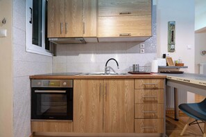 Eine kleine Küche mit Holzausstattung, einem eingebauten Backofen und einem Spülbecken.