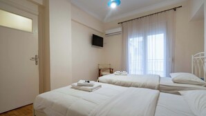 Una camera d'albergo con due letti, televisore, condizionatore e finestra con tende.