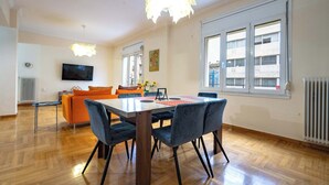 Un soggiorno moderno con zona pranzo, pavimento in legno, televisore a schermo piatto e ampie finestre.