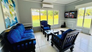 A living room with blue sofas, a coffee table, and a TV on the wall. - Beachfront House in El Tamarindo (El Tamarindo)