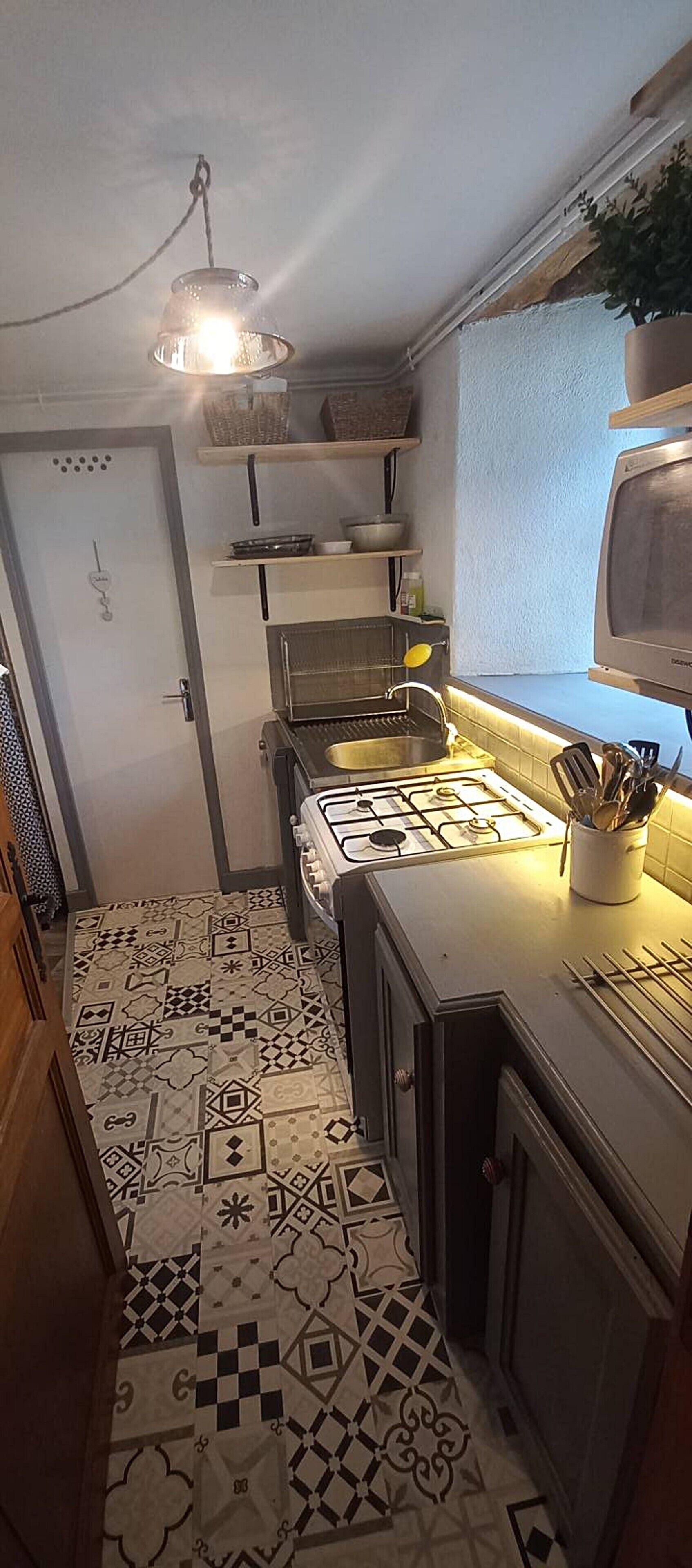 Ett kök med en gasspis, en mikrovågsugn och en hängande lampa.
