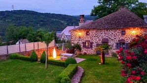 Un edificio de piedra con un jardín cuidado, una pequeña mesa y un sendero.