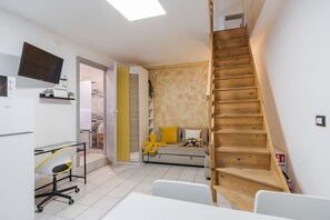 A modern living space with a staircase, a sofa with cushions, a desk with a chair, and a flat-screen TV mounted on the wall. - Casa Bruno Terrace Charm by Wonderful Italy (Catania)