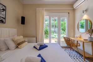 Une chambre d’hôtel avec un lit, un bureau, une chaise, une plante en pot et une vue sur la verdure.