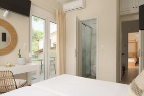 A hotel room with a bed, a desk with a chair, a potted plant, and a sliding glass door leading to a balcony. - Kipo Paradiso 6 Spa Yoga & Gym Resort (Rethymno)