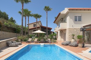 A swimming pool with lounge chairs and palm trees. - Kipo Paradiso 6 Spa Yoga & Gym Resort (Rethymno)