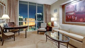A modern hotel room with a large window offering a city view, a comfortable sofa, a dining table, and a small side table. - 30th Floor Strip Views MGM Signature (Las Vegas)