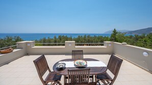 A terrace with a table and chairs, overlooking a coastal view. - Gallery House (Viannos)