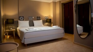 A modern hotel room with a large bed, bedside tables, a mirror, and a wardrobe. - Anaroussa Diros Villa (East Mani)