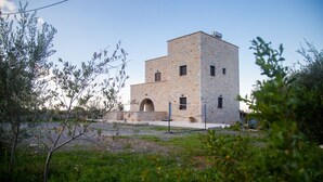 A two-story building with a stone facade and an arched entrance. - Anaroussa Diros Villa (East Mani)