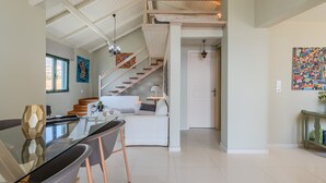 A spacious living area with a staircase, a dining table, and a kitchen in the background. - Gallery Apartment (Viannos)