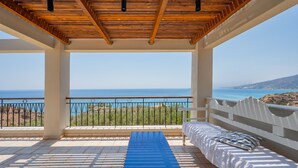 A balcony with a view of the sea, a blue mat, and a bed with a pillow. - Gallery Apartment (Viannos)