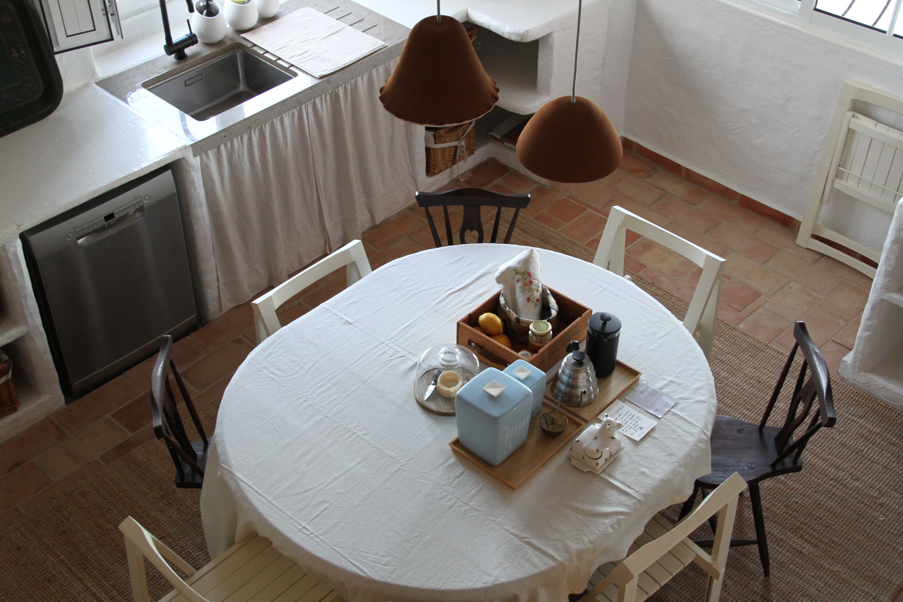 Una cocina con lavavajillas, un lavabo y una zona de comedor con una mesa redonda y sillas.