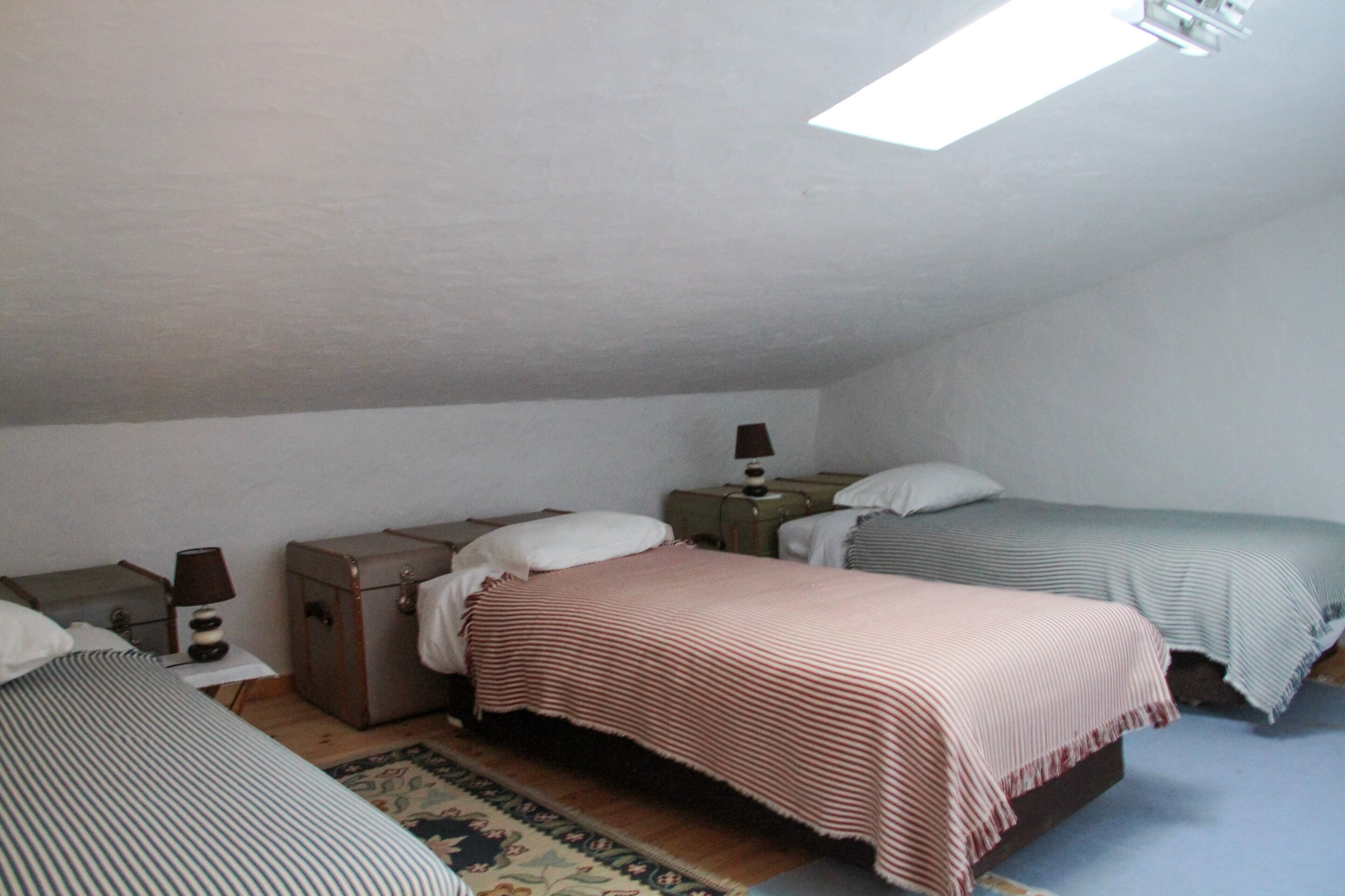Una camera da letto con due letti, un tavolino, una lampada e una valigia.