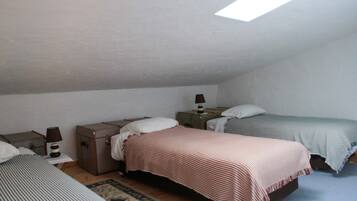 Una camera da letto con due letti, un tavolino, una lampada e una valigia.