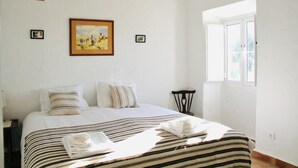 Een hotelkamer met een bed, een schilderij aan de muur, een raam en een tafeltje.