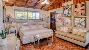 Une chambre à coucher avec un grand lit, une table de chevet, une lampe de chevet, un ventilateur de plafond et un plancher en bois.