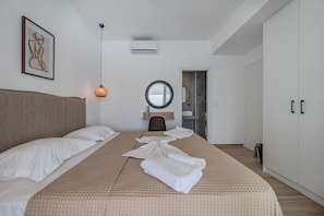 A modern hotel room with a large bed, a round mirror, and a wardrobe. - Mythos 8 Villa (Agios Vasileios)