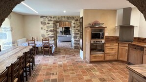Uma cozinha rústica com paredes de pedra, armários de madeira e chão de azulejos.