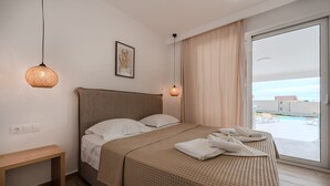 Ein Hotelzimmer mit Bett, Nachttisch, Pendelleuchte und Blick ins Freie.