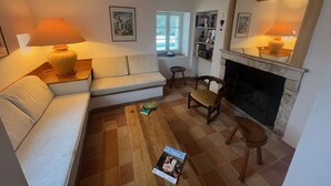 Una sala de estar acogedora con un sofá, una mesa de centro, una chimenea y una estantería.