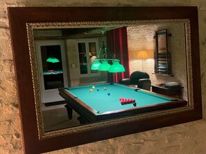 A pool table with balls, a chair, and a lamp.
