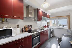 A modern kitchen with stainless steel appliances, a built-in oven, and a large window offering a view. - Aveiro – The Little Venice of Portugal (Aveiro)