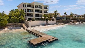 A multi-story hotel with balconies overlooking a beach and clear turquoise waters. - Bellevue Penthouse 10 (Kralendijk)