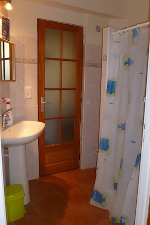 Een badkamer met een houten deur, een wastafel en een douchegordijn.