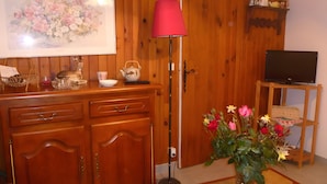 A wooden cabinet with drawers, a floor lamp, a vase with flowers, a television on a stand, and a framed picture on the wall. - Apartment 'L'Appartement Du Moulin' with Private Terrace and Wi-Fi (Mascaras)