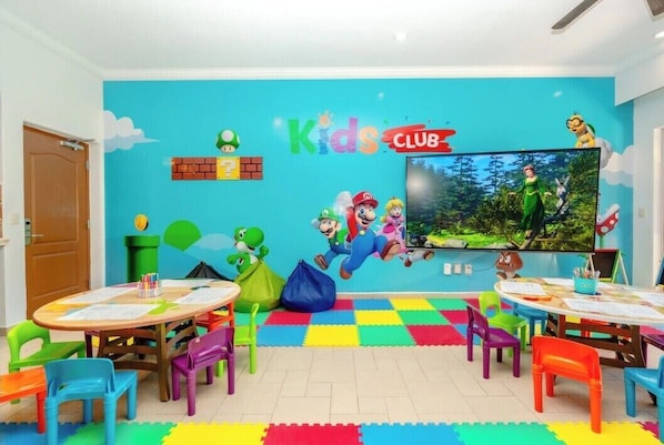 A children's playroom with colorful furniture, a large TV, and Mario-themed decorations.