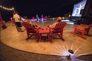 An outdoor seating area with red chairs and a stage for performances.