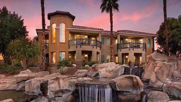 Un hotel con cascada, varios balcones y un jardín ajardinado.