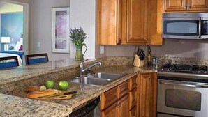 Una cocina con encimeras de granito, armarios de madera y electrodomésticos de acero inoxidable, incluyendo un lavavajillas.